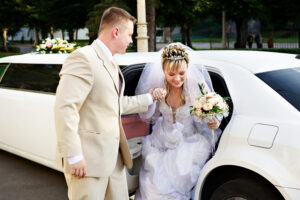 Happy bride and groom out of wedding limousine